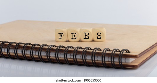word FEES made with letters on wooden blocks on the wooden notepad
