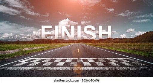 The word finish behind the tree of empty asphalt road at golden sunset and beautiful blue sky. 