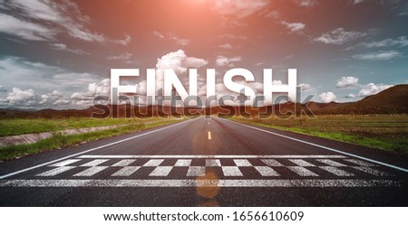 The word finish behind the tree of empty asphalt road at golden sunset and beautiful blue sky. 