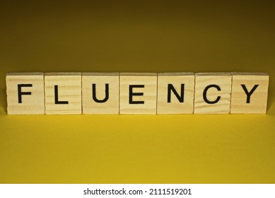 Word Fluency Made From Wooden Letters Lies On A Yellow Table