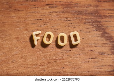 Word Food Formed With Alphabet Soup Pasta Letters On A Wooden Background. Concept: Fun With Food