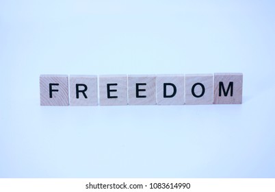 The word freedom written with wooden squares and isolated on a white background.