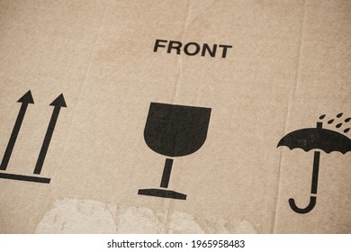 Word Front And Three Symbols On Cardboard Box - This Way Up, Keep Dry And Fragile For Careful Transportation. Close-up.