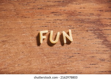 Word Fun Formed With Alphabet Soup Pasta Letters On A Wooden Background.