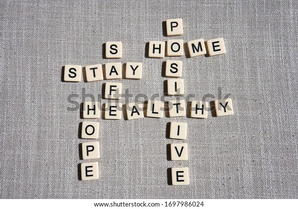 Word game with\
crossword grids showing various words - stay, home, hope, healthy,\
safe, and positive - isolated on gray cotton background. Stay home\
and be positive concept.