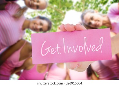 The word get involved and young woman holding blank card against smiling women in pink for breast cancer awareness