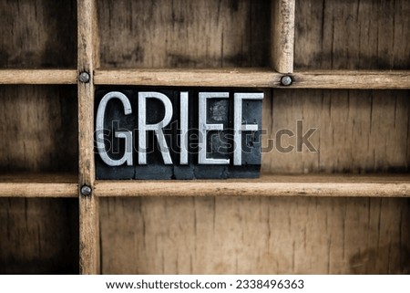 The word -GRIEF- written in vintage metal letterpress type in a wooden drawer with dividers.