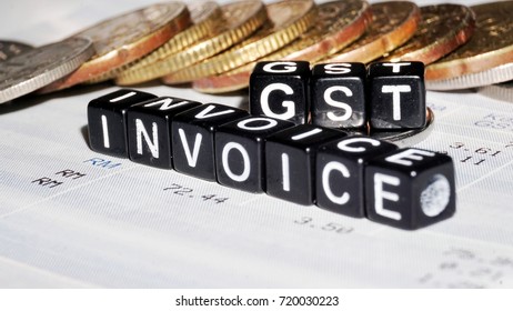 Word GST Invoice From Black Plastic Cube On Blur Coin And Receipt Background. Selective Focus.