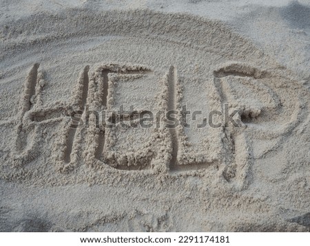 The word HELP written in the sand on the beach. Tourist writing letters H. E. L. P. by hand on dry sand. The concept of a call for help. Word drawn in the sand