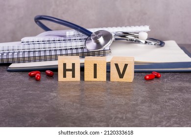 the word HIV is written on wooden cubes near a stethoscope on a paper background. medical conceptual word collected of wooden elements with the letters. HIV - short for Human Immunodeficiency Virus.