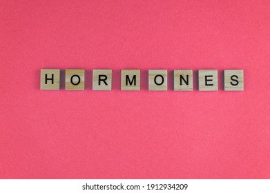 Word Hormones. The Phrase Is Laid Out In Wooden Letters. Top View. Motivation. Women Health. Pink Background. Copy Space.