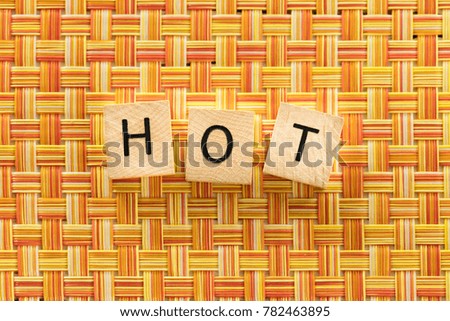 The word hot spelled out on a bright orange background on wooden tiles