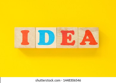 The word "idea" of wooden cubes. Letters on a yellow background. The concept of thought. 