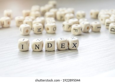 Word Index made with block wooden letters cubes in centre surrounded by pile of other letters on wooden surface. SEO concept