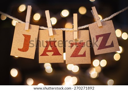The word JAZZ printed on clothespin clipped cards in front of defocused glowing lights.