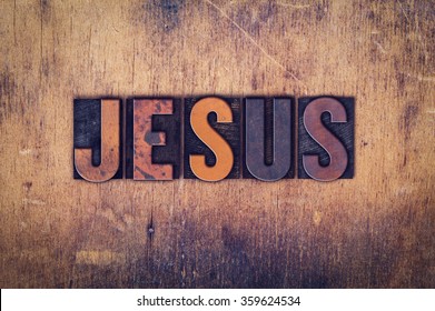 The word "Jesus" written in dirty vintage letterpress type on a aged wooden background.