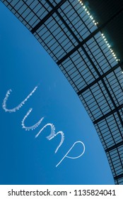 The word Jump written in the sky by skywriter with a stadium roof line in silhouette in the foreground