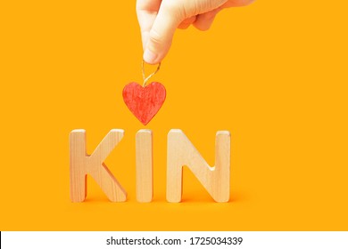 Word kin on orange background. Family concept. Hand holds heart over the word kin - Shutterstock ID 1725034339