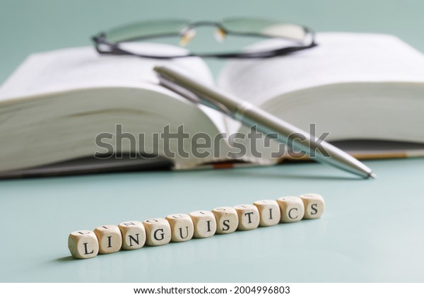 The word
linguistics is written next to open book, pen and. Concept for the
study of linguistics at school, college and university. Pastel
background. Selective focusing.
Close-up