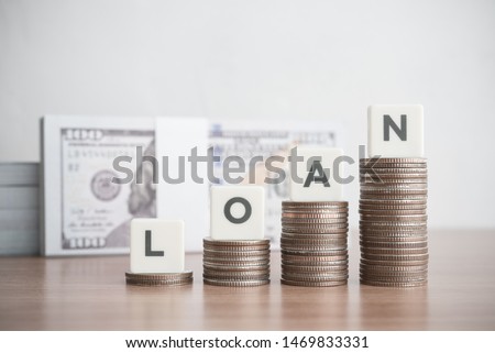 Word LOAN on step stack coins as graph up with banknotes background. Business and finance concept. Interest and fees from loans are main revenue for banks. Loans can be unsecured such as credit card.