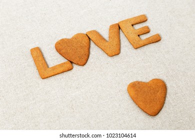 The word Love from homemade cookies with ginger on canvas natural tablecloth. Cookies in heart shape. Selective focus and Copy space.