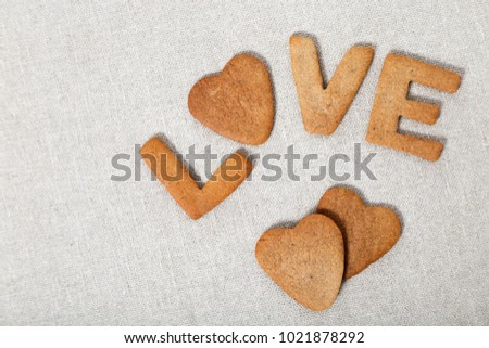 The word Love from homemade cookies with ginger on canvas or cotton material. Cookies in heart shape. Flat lay and Copy space.