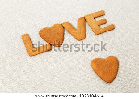 The word Love from homemade cookies with ginger on canvas natural tablecloth. Cookies in heart shape. Selective focus and Copy space.