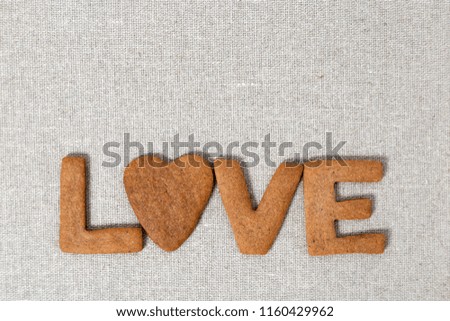 The word Love from homemade shortbread cookies with ginger on linen fabric. Cookies in heart shape. Flat lay and Copy space.