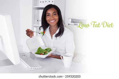 The Word Low Fat Diet Against Happy Pretty Businesswoman Eating A Salad At Her Desk