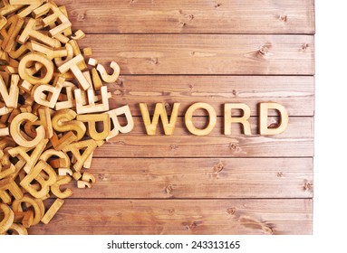 Word word made with block wooden letters next to a pile of other letters over the wooden board surface composition