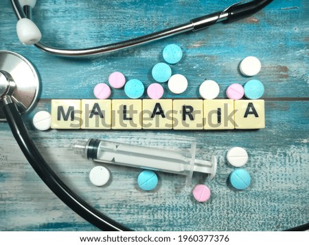 Word MALARIA , on a table with a stethoscope,syringe and pills. Medical concept.