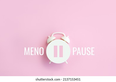 Word Menopause, pause sign on a white alarm clock on pink background. Minimal concept hormone replacement therapy. Сopy space