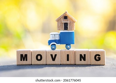 Word MOVING Made Of Wooden Letter Blocks On A Tree Stump With A Toy Truck Having A Tiny House On Top. Residential Moving Service Concept.