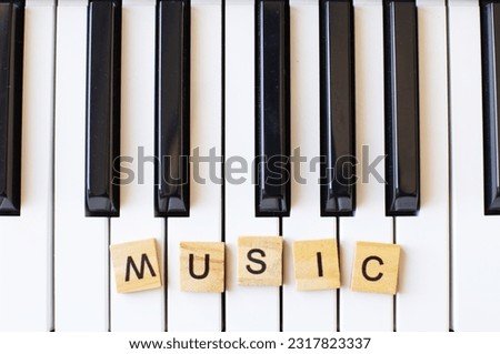 Word music made by wooden cubes on a s ynthesizer keys black and white background with copy space for your text. Piano octave close up top view. Keyboard musical instrument. Music class conceptt