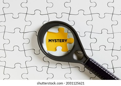 The word mystery on missing puzzle piece with a magnifying glass. To investigate or solve a mystery concept.