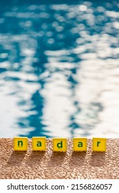 Word Nadar Which Means To Swim In Spanish Made Of Scrabble Type Letters By The Edge Of Swimming Pool. 