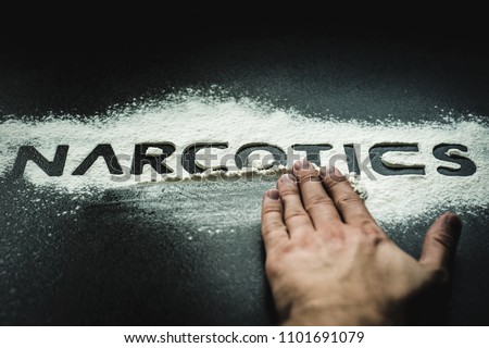 Word NARCOTICS reflected on white powder imitating drugs. Concept of health and medicine. Problems and drug addiction. The NARCOTICS inscription smeared with the hand.