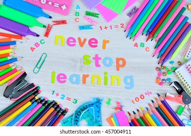 word never stop learning with stuff for school on gray wooden table