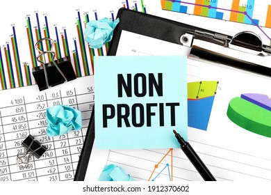 Word NON PROFIT On Stickers. Clipboard With Charts, Pen And Stationery On Office Desk. Accounting Concept Top View.