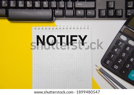 the word notify iwritten on a yellow and white background near a computer keyboard and calculator.  
