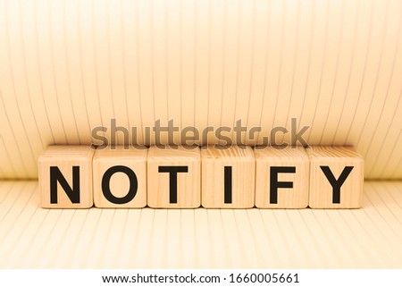 Word NOTIFY on wooden cubes on a notebook background