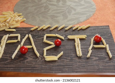 The Word PASTA, Laid Out On The Table With Macaroni And Cherry Tomatoes