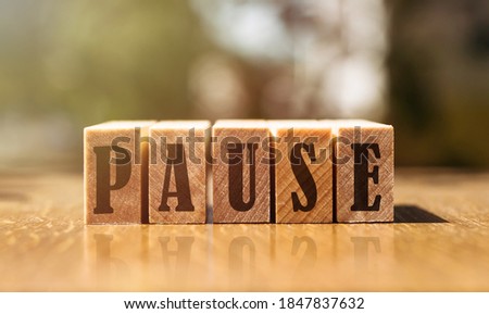 The word pause with wooden blocks on the table in the sunlight.