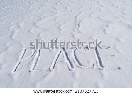 The word peace is written in the snow. Letters calling for the unification of countries around the world. The concept of peaceful coexistence of the population. Text to write in the snow