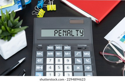 Word PENALTY on the display of a calculator on office desk