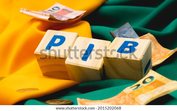The word PIB ( gross domestic product )\
written on wooden cubes with some Brazilian Real banknotes and\
coins on yellow and green fabrics, making reference to Brazil.\
Brazilian Portuguese\
language.\
