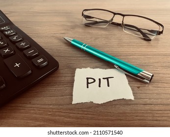 Word PIT with pen, calculator and glasses on office desk, personal tax income in Poland concept - Shutterstock ID 2110571540