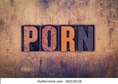The word "Porn" written in dirty vintage letterpress type on a aged wooden background.