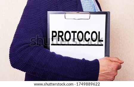 The word PROTOCOL written in white paper on a tablet held by a man