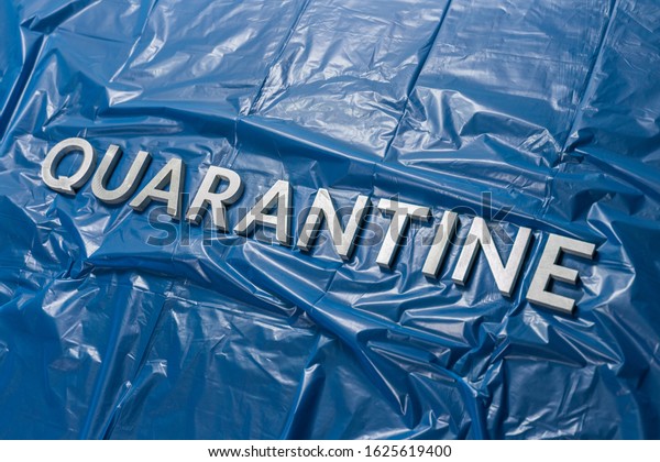 the word quarantine laid\
with silver letters on crumpled blue plastic film in diagonal\
perspective